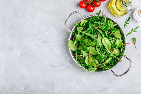 Mix of spring fresh leaves with arugula, lettuce, spinach, beets. Ingredients for salad on a gray stone background.の写真素材