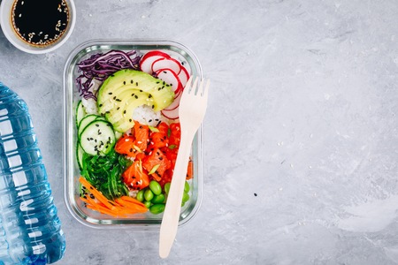 Poke meal prep containers with salmon, rice, radish, cucumber and avocado. Top view, copy spaceの写真素材