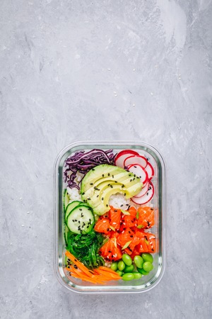Poke meal prep containers with salmon, rice, radish, cucumber and avocado. Top view, copy spaceの写真素材