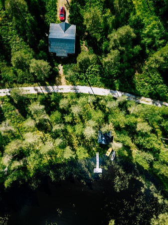 Aerial view of blue lake with green forests on a sunny summer day in Finland. Wooden house, sauna, boats and fishing pier by the lake.の写真素材
