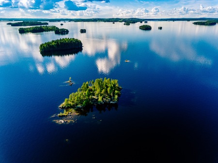 Aerial view small island in blue lake landscape with green forests on a sunny summer day in Finland. Drone photography from aboveの写真素材