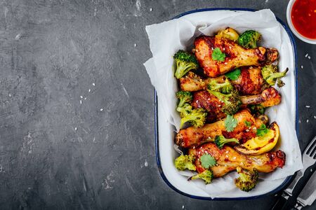 Baked chicken drumsticks with broccoli, cilantro, sesame and sweet chili sauce on a gray stoneの写真素材
