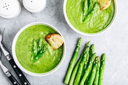 Asparagus cream soup with croutons on gray stone background, top view. Green summer vegetable soup.の写真素材