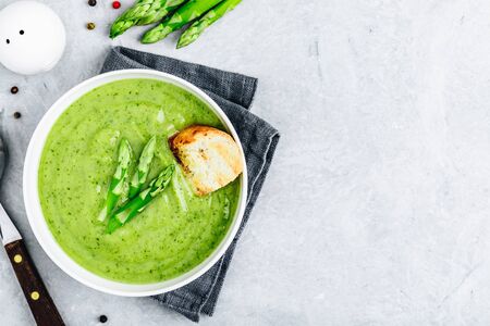 Asparagus cream soup with croutons on gray stone background, top view. Green summer vegetable soup.の写真素材