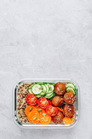 Meal prep lunch box containers with quinoa, meatballs cucumbers, carrots, sesame and pumpkin seedsの写真素材