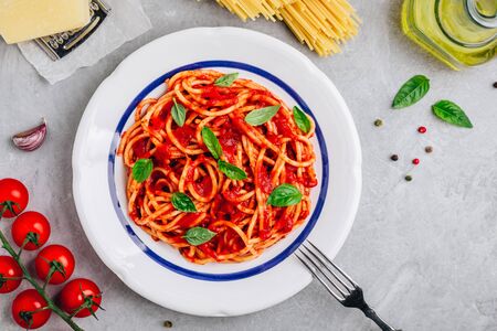Italian spaghetti pasta with tomato sauce, basil and parmesan cheese on gray stone background. View from above, top view.の写真素材