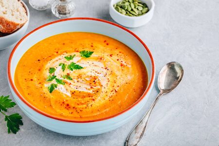 Carrot and pumpkin cream soup with parsley on gray stone background.の写真素材