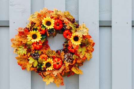 Thanksgiving Autumn wreath with sunflowers, pumpkins and maple leaves on wooden doorの写真素材