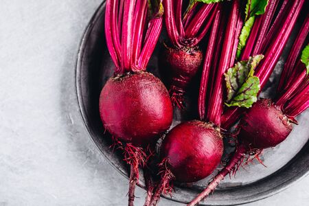 Bunch of fresh raw organic beets with leaves on a gray stone background
