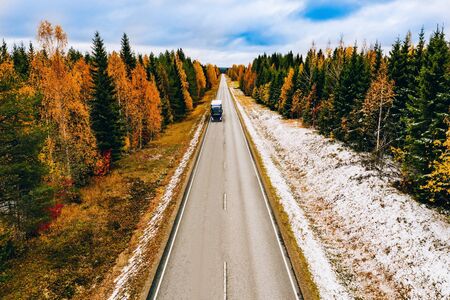 Aerial view of first snow autumn color forest and a road with car in Finland Lapland.