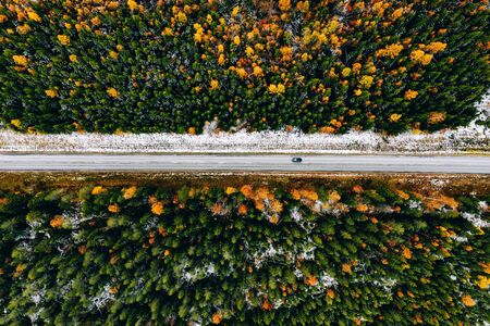 Aerial view of first snow autumn color forest and a road with car in Finland Lapland.