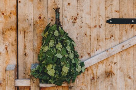 Birch sauna broom on wooden rustic sauna door in Finlandの写真素材
