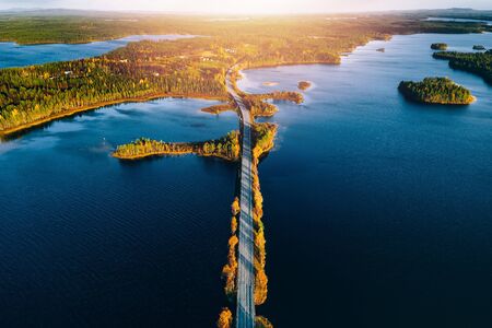 Aerial view of bridge across blue lakes with sun light in colorful autumn forest in Finland Lapland.の写真素材