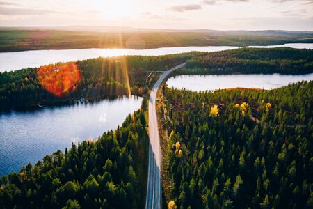 Aerial view of bridge across blue lakes with sun light in colorful autumn forest in Finland Lapland.の写真素材