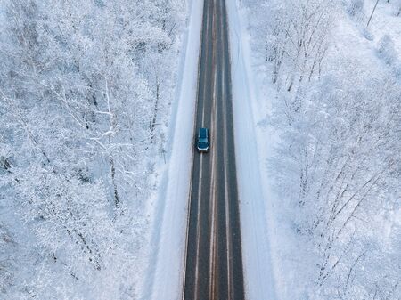 Aerial view of a winter road with snow covered forest 