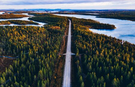 Aerial view of road through autumn forest with blue lakes in Finland Lapland.の写真素材