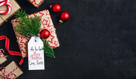 Christmas background with fir branches and a gift box with a red bow on a dark concrete background....