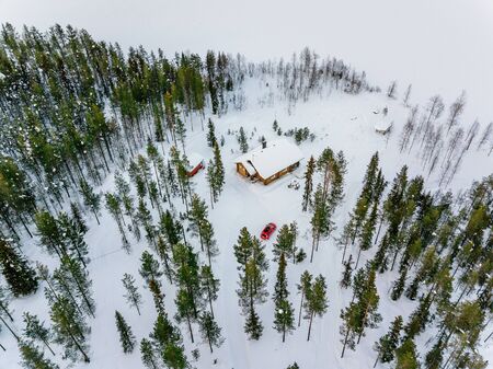 Aerial view of wooden log cabin or cottage in snow  winter forest by the lake in rural Finland Laplandの写真素材