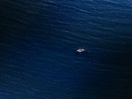 Aerial view of wooden fishing boat in deep blue sea or lake.の写真素材
