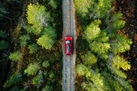 Aerial view of red car for traveling with a roof rack on a country road in Finlandの写真素材