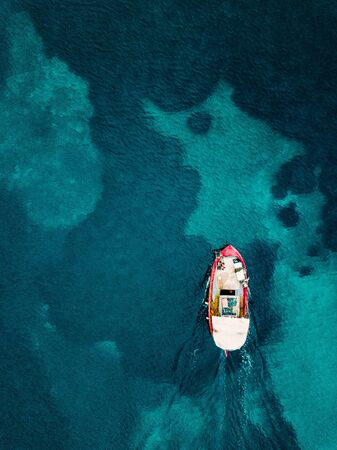 Aerial view of old wooden fishing boat in blue sea in Greece.
