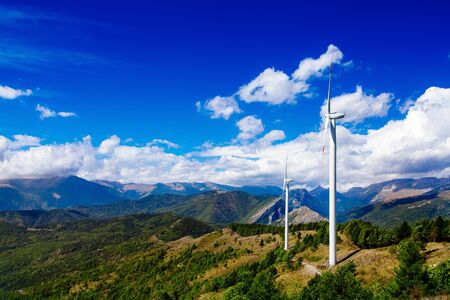 Aerial view of wind turbine farm. Wind power plants in green summer landscape with clouds in Italy.