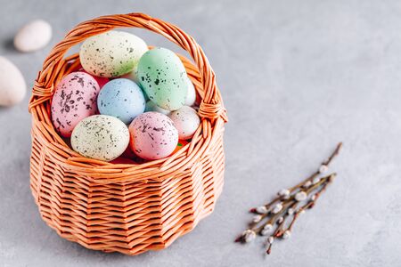 Colorful Easter eggs in the basket on gray stone concrete background, copy space. Happy Easter...