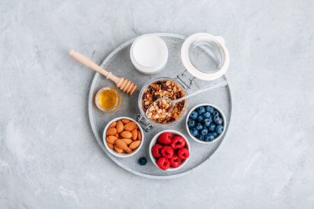 Granola cereals with fresh berries, almonds, milk and honey. Ingredients for healthy breakfast.