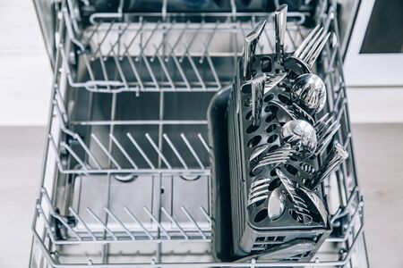 Open dishwasher machine with clean utensil close-up after washing.の写真素材