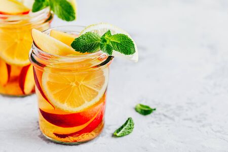 Cold peach and lemon iced tea. Summer refreshing drink with peach, lemon and ice.の写真素材