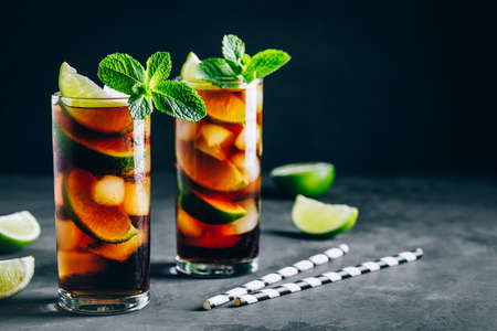 Rum and  Cuba Libre ice cold drink cocktail with lime and mint on dark background.の写真素材