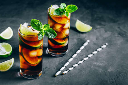 Rum and  Cuba Libre ice cold drink cocktail with lime and mint on dark background.の写真素材