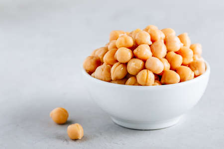 Cooked Chickpeas in white bowl on gray stone background, copy space. Ingredient for hummus dip.の写真素材