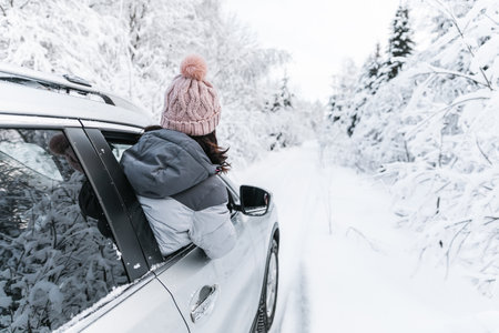 Young woman traveling in car on winter road and snow covered forest.の写真素材