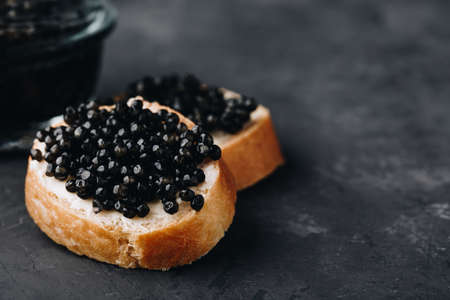 Black caviar sandwiches with butter on dark concrete backgroundの写真素材
