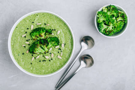 Broccoli cream soup with sunflower and sesame seeds. Green vegetarian summer soup, top view.の写真素材