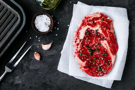 Raw veal beef steak on a paper with salt and thyme on dark stone concrete background. Top view with copy space.の写真素材