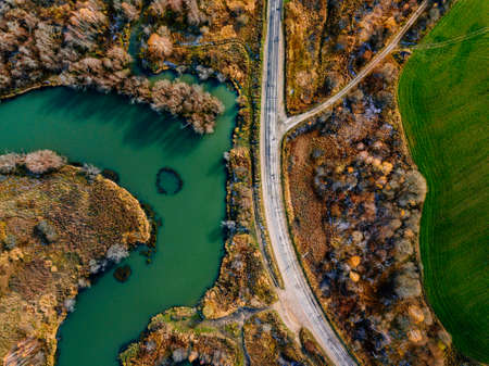 Aerial view of winding river and road in golden colored autumn or fall forestの写真素材