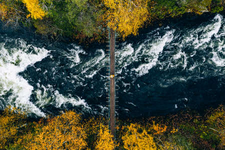 Aerial view of fall forest and blue river with bridge in Finland. Beautiful autumn landscape.の写真素材