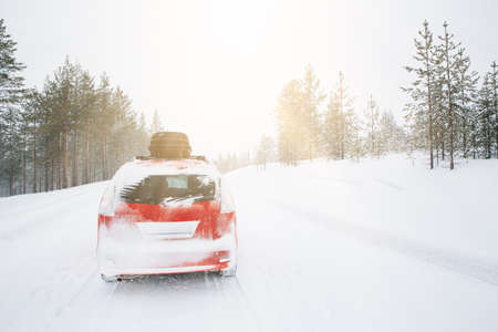 Red car with roof box on winter snow road. Snow winter forest with red car on the road.の写真素材