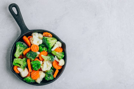 frozen vegetables. Frozen carrots, broccoli and cauliflower in cast iron pan ready to cook, top view with copy spaceの写真素材