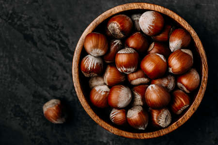 hazelnuts. Whole Hazelnuts in wooden bowl on dark background, top view.の写真素材