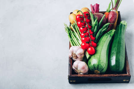 Fresh organic vegetables in a wooden box. Potatoes, zucchini, beets, carrots, garlic, asparagus, tomatoes, green beans.の写真素材