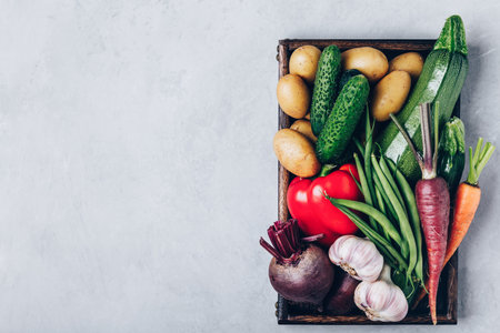 Fresh organic vegetables in a wooden box, top view with copy space. Potatoes, zucchini, beets, carrots, garlic, pepper, cucumbers, green beans.の写真素材