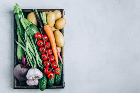 Fresh organic vegetables wooden box with potatoes, zucchini, tomatoes, green beans, carrots, garlic, cucumbers and beets. healthy eating concept.の写真素材