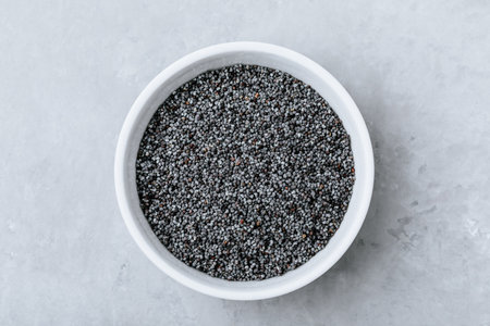 Poppy Seeds.Dry raw poppy seeds in bowl on gray stone background. Top view with copy space.の写真素材