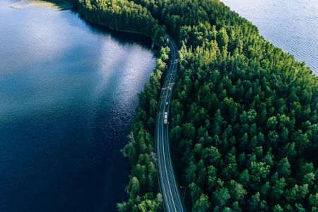 Aerial view of road in green woods and blue lakes water in summer Finlandの写真素材