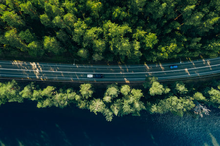 Aerial view of road with green woods by blue lakes water in summer Finland.の写真素材