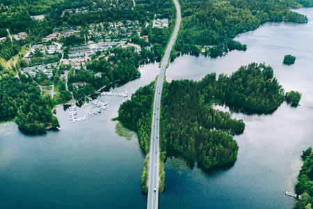 Aerial view of road bridge with cars between green forests and blue lakes in rural Finland. beautiful summer landscapeの写真素材