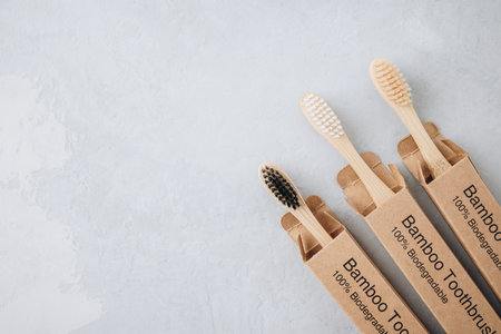 Bamboo toothbrushes. Eco friendly bamboo toothbrushes on gray stone background, top view with copy...